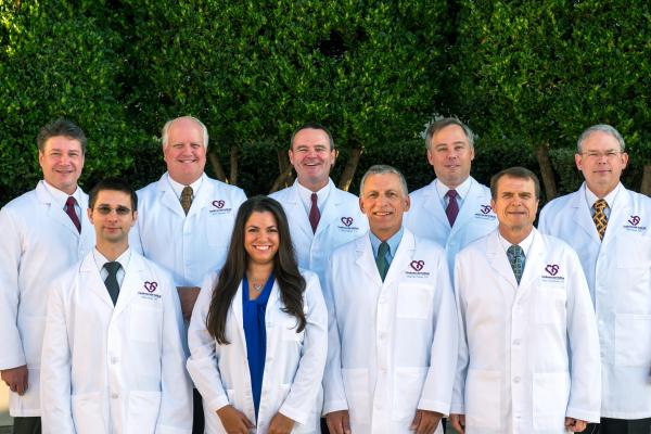 A diverse team of healthcare professionals specializing in heart health, in white lab coats posing confidently outdoors, symbolizing teamwork and expertise in medicine.