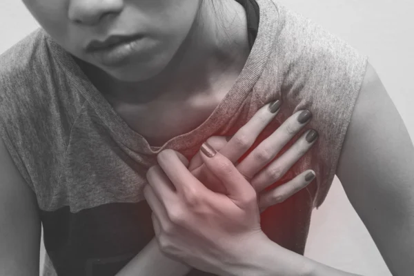 A person clutching their chest in discomfort or pain, expressing a sense of distress or health concern, may need to see a cardiologist.