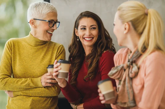 Three women of different ages enjoying a warm and lively conversation over coffee, discussing heart health.