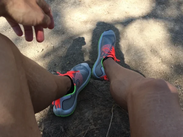 A person resting on a sunny day, showcasing their brightly colored sneakers with a hand reaching towards one shoe, reflecting the importance of heart health.