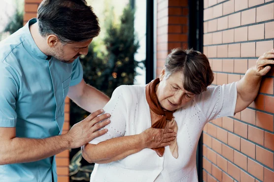 A healthcare professional attentively assisting an elderly woman who appears to be experiencing discomfort or pain related to venous disease, possibly in a medical or caregiving setting.
