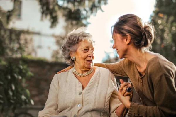 A heartfelt moment between generations: a young woman engaging in a warm conversation with an elderly lady, who listens intently with a smile at the Cardiovascular Institute of the South, illustrating the timeless bond of