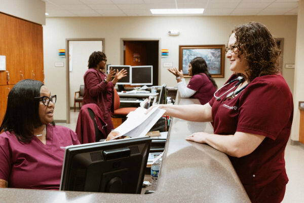A lively nurses station at CIS, with several nurses in burgundy scrubs engaging in conversation