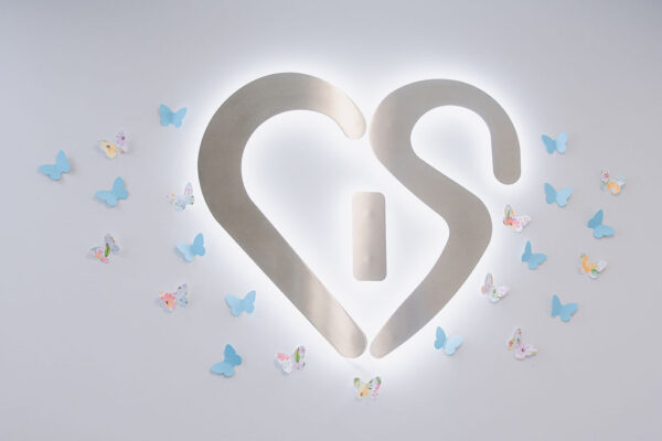A backlit metal CIS sign with paper butterflies surrounding it