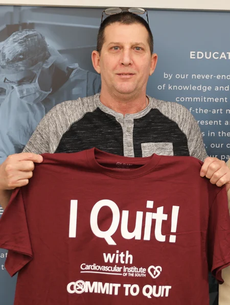 Man proudly holding up a t-shirt with the message "I quit!" celebrating his accomplishment with the Cardiovascular Institute of the South's "commit to quit" program.