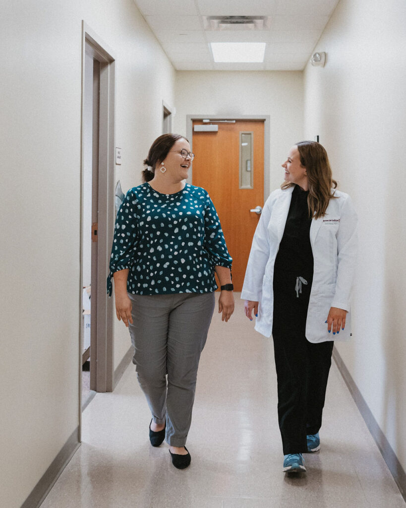 A doctor and a patient having a pleasant conversation while walking down a hallway at CIS