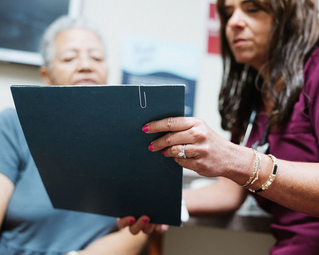 A CIS nurse looks over a chart with a patient