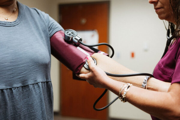 A close up shot of a CIS nurse checking a patient's blood pressure