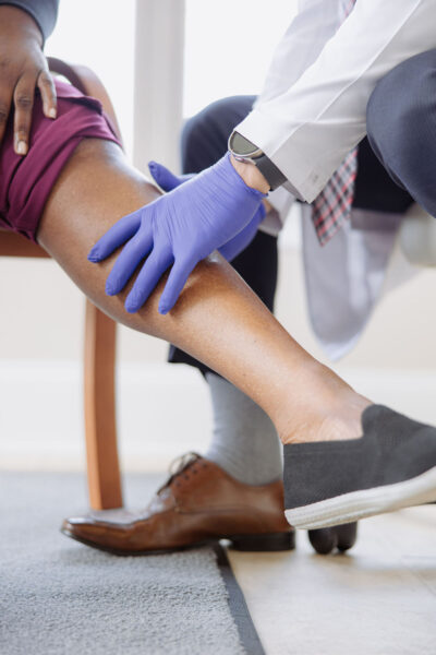 A CIS doctor checks a patient's lower leg for signs of Deep Vein Thrombosis (DVT)