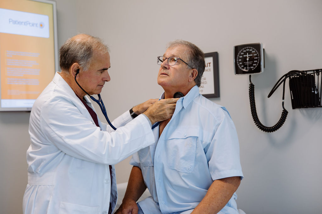 Dr. Craig Walker listens to a patient's carotid artery with a stethoscope
