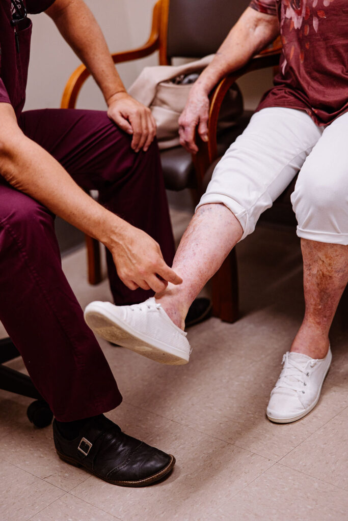 A nurse examines the veins on a patient's lower leg for signs of peripheral artery disease (PAD)