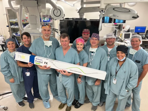 A group of CIS staff members in scrubs pose with a box containing the Medtronic Evolut FX catheter system