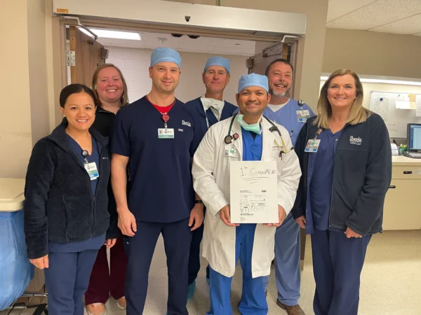 A group of CIS staff poses with a box containing the CardioMEMS™ HF System