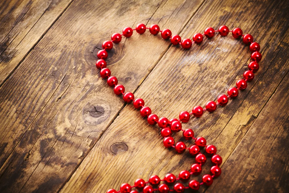 A heart shape formed with red beads on a rustic wooden background, symbolizing the focus on heart health at the Cardiovascular Institute of the South.