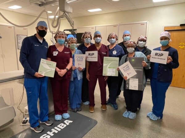 A group of CIS staff members pose with boxes containing components for the Diamondback 360® Extended Length Peripheral Orbital Atherectomy Device (OAD) after preforming a successful PAD treatment through the wrist
