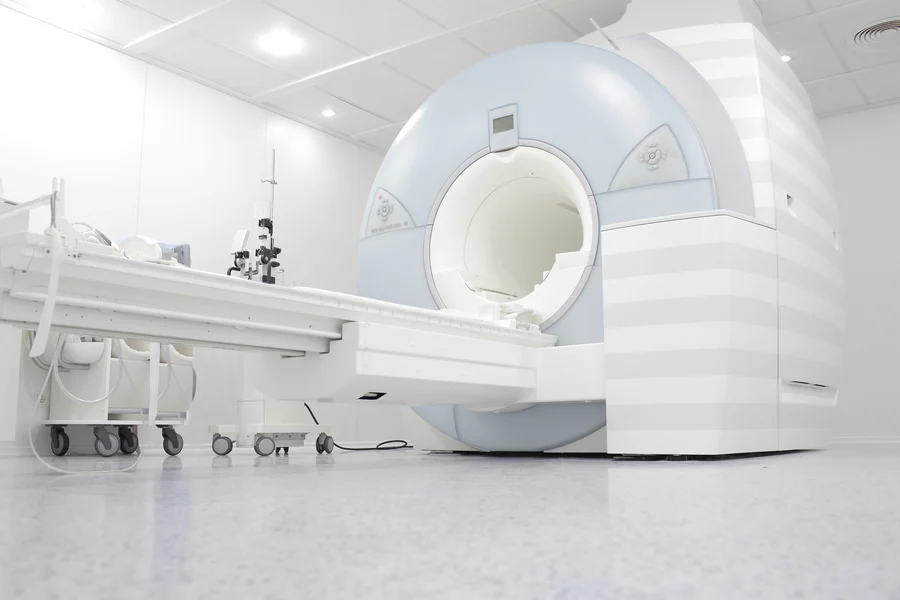 A modern MRI machine in a clean and bright medical imaging room, specializing in cardiology, with an adjacent patient bed.