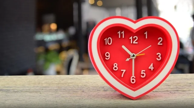 Love every moment - heart-shaped clock on a wooden surface with a blurred background, symbolizing Heart Health.