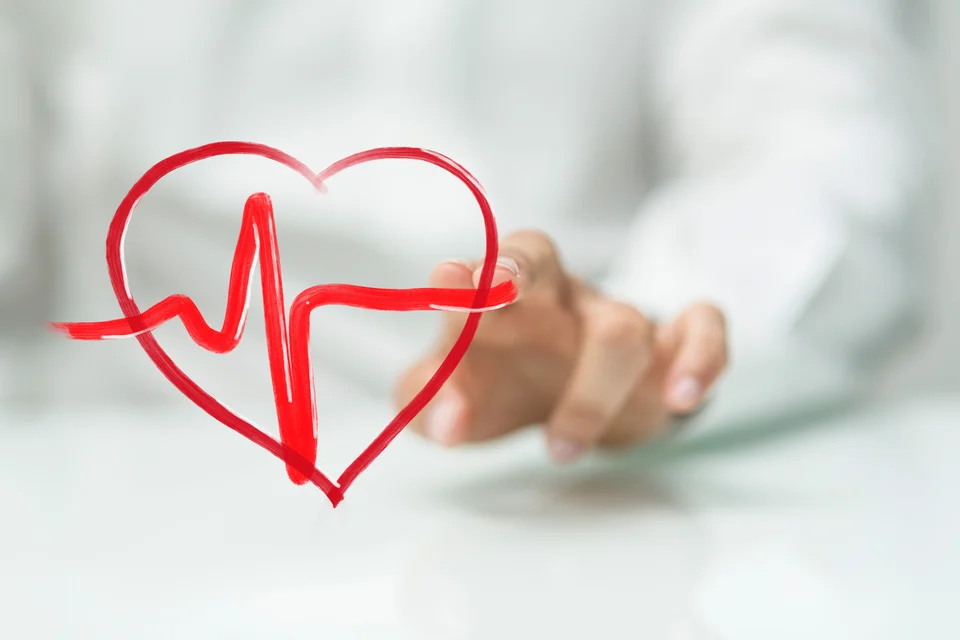 A hand reaching towards a drawn heart with an ekg pulse line, symbolizing healthcare, love, or life-saving support by a cardiologist.