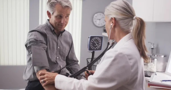 A cardiologist checking a patient's blood pressure during a medical consultation.