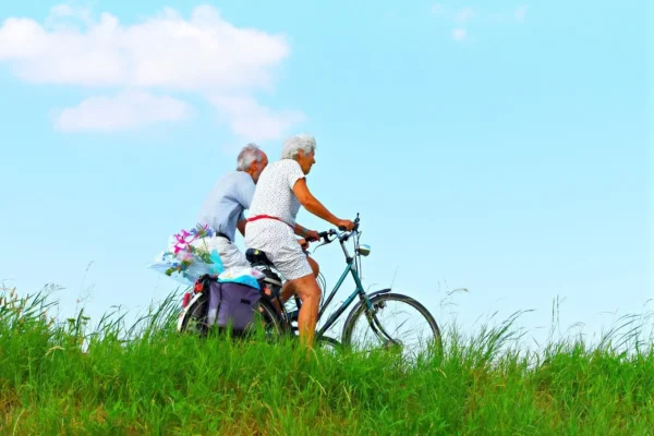 Elderly couple enjoying a leisurely bike ride together on a bright, sunny day, benefiting their heart health.