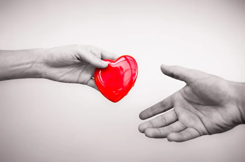 Handing over care: a symbolic gesture of a red heart being passed from one hand to another, embodying kindness, love, and compassion by a cardiologist.