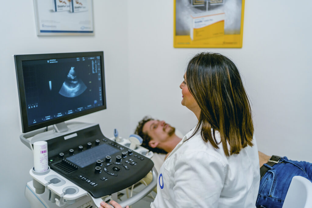 Man having a cardiology ultrasound with a technician monitoring the screen