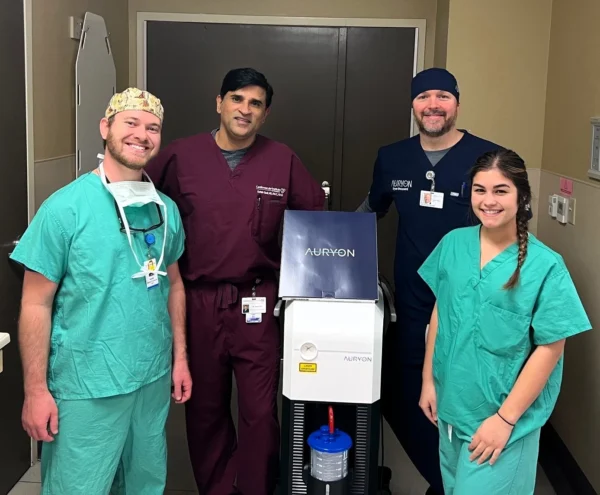 A team of medical professionals posing proudly with a new piece of medical equipment in a hospital setting.