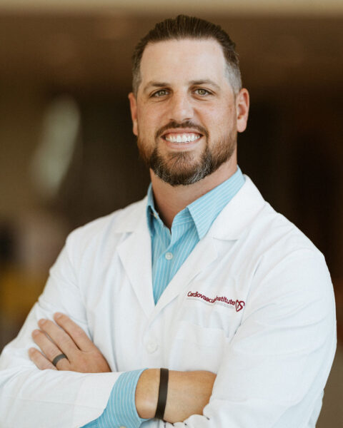 Confident healthcare professional smiling in a white lab coat with crossed arms.