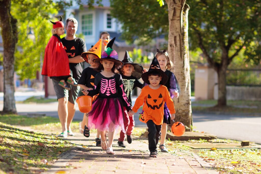 Children in Halloween costumes going trick or treating with a chaperone