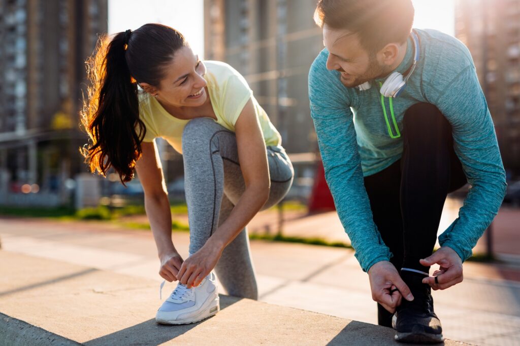 A woman and a man tightening their shoelaces for an outdoor run