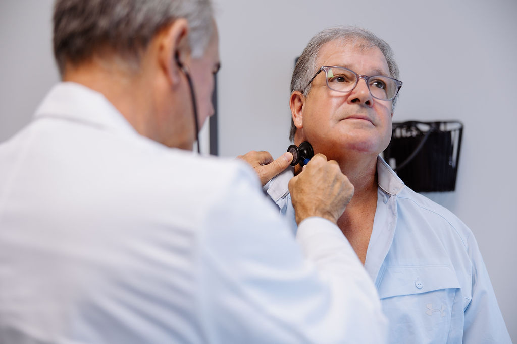 Vascular specialist inspecting patient, placing a stethescope to his neck.