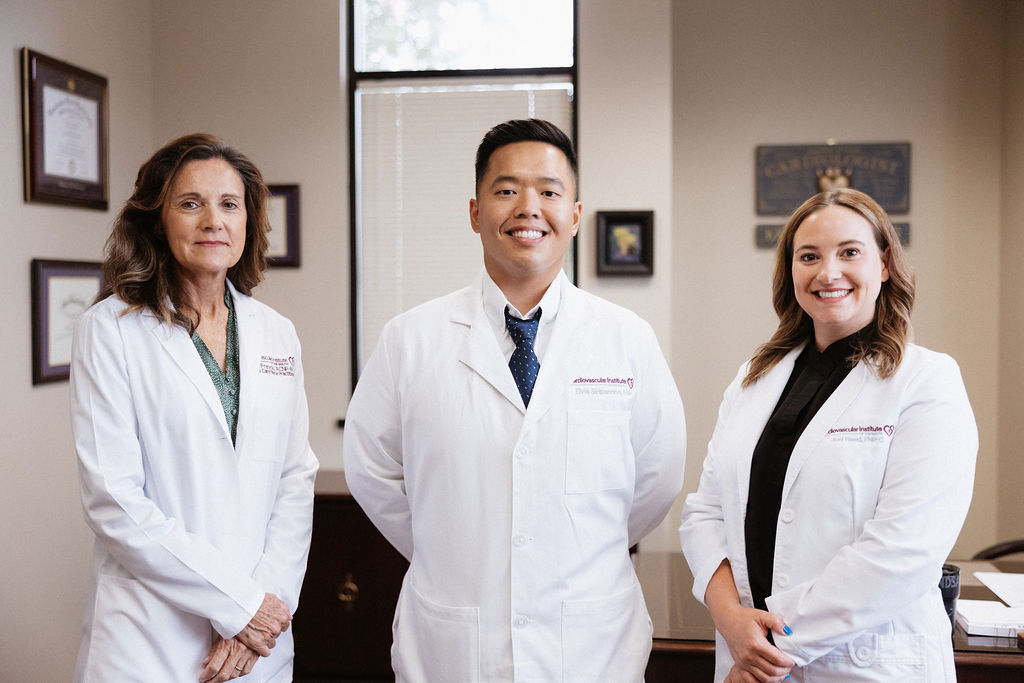 Three vascular specialists in white lab coats standing side by side, smiling.