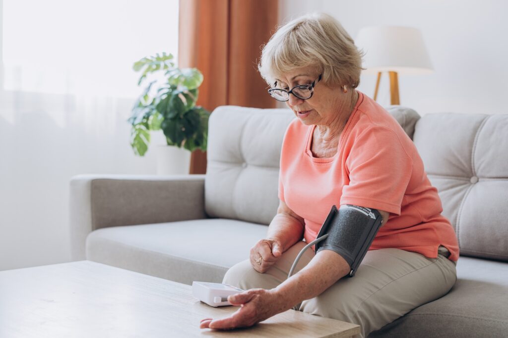 Senior woman with hypertension measuring blood pressure herself at home.
