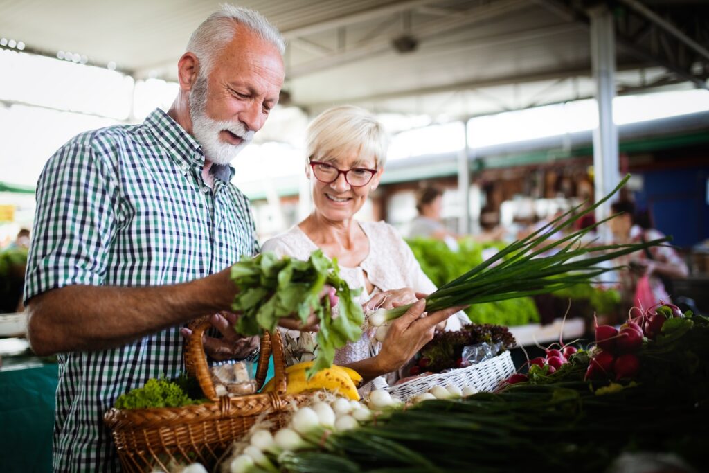 Elderly husband and wife shopping for fresh produce together at the grocery store