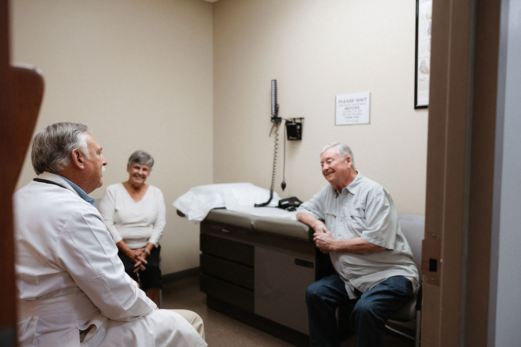 Doctor consulting with elderly husband and wife in clinic office