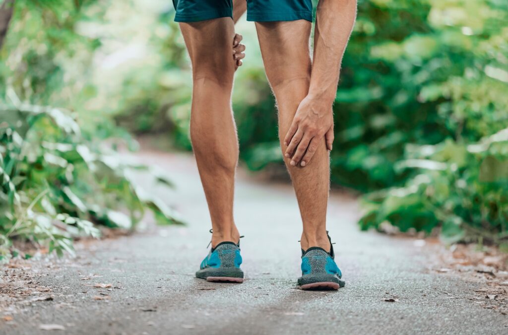 Man touching his calf in pain while out for a run