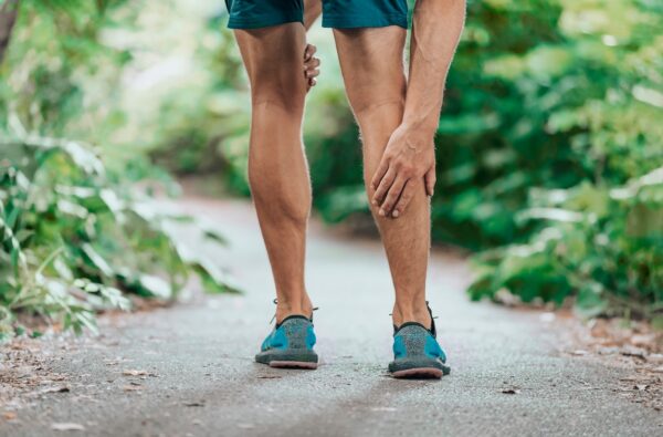 Man touching his calf in pain while out for a run
